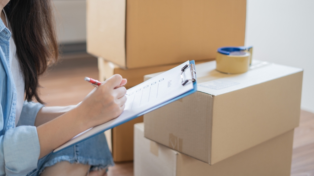 woman making checklist by moving boxes
